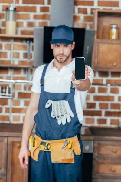 Beau jeune maître professionnel à la maison montrant smartphone avec écran blanc — Photo de stock