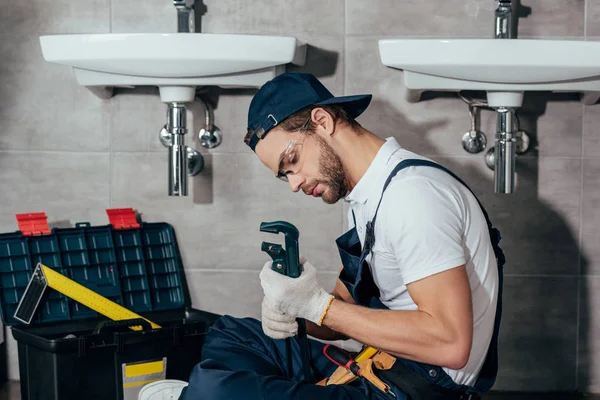 Young professional plumber fixing sink in bathroom — Stock Photo