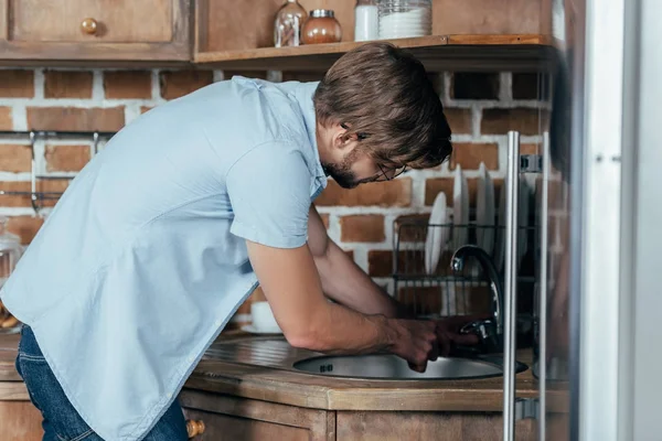 Vue latérale du jeune homme réparant l'évier à la maison — Photo de stock