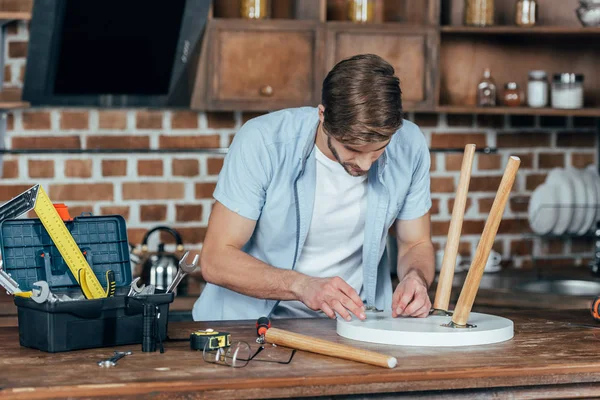 Ocasional joven reparación de taburete con herramientas en casa — Stock Photo