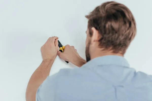 Задний вид молодого мастера с помощью плоскогубцев и снятия ногтей со стены — стоковое фото