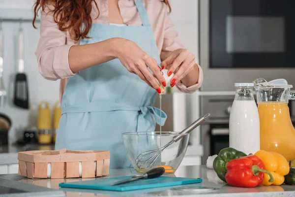 Image recadrée de la femme versant l'oeuf dans un bol en verre — Photo de stock