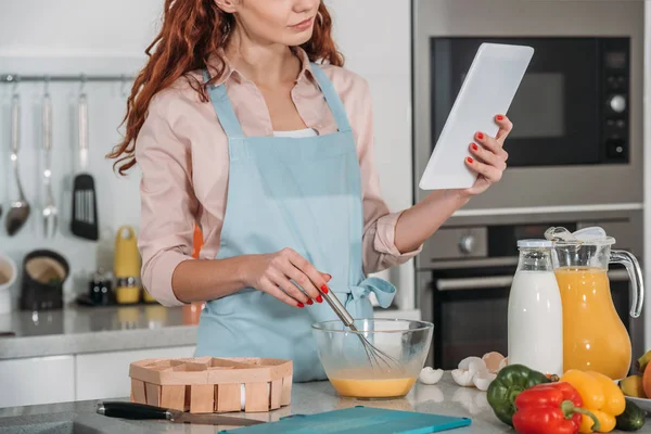 Обрезанный образ женщины, глядя на рецепт приготовления пищи — стоковое фото