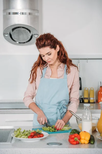 Mujer cortando verduras para ensalada en la cocina - foto de stock
