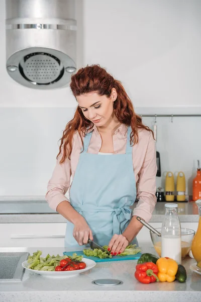 Woman cutting vegetables for salad in kitchen — Stock Photo