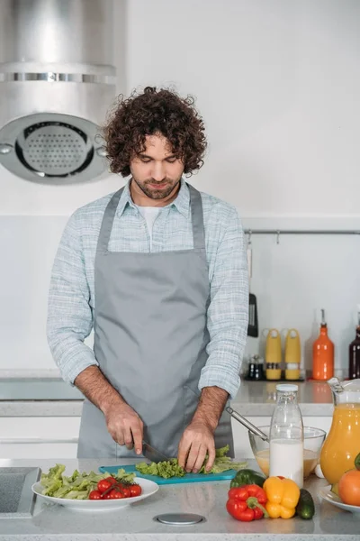 Bell'uomo che taglia verdure per insalata — Foto stock