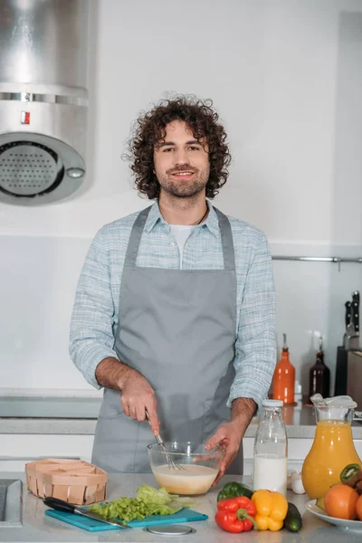 Schöner Mann bereitet Teig zu und schaut in die Kamera — Stockfoto