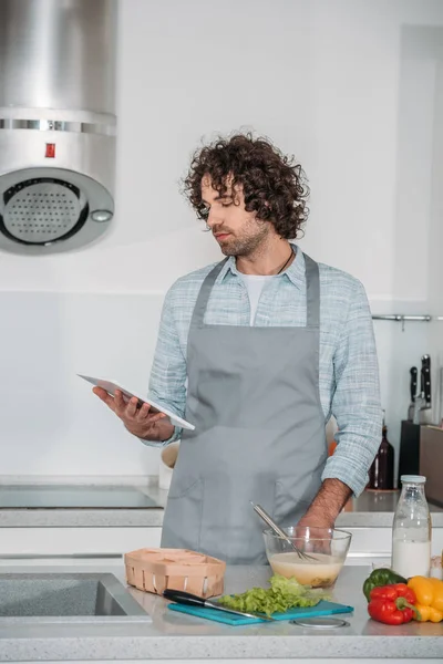Handsome man searching for recipe and looking at tablet — Stock Photo