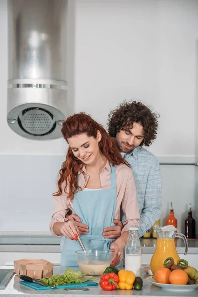 Novio abrazando novia mientras ella preparación bateador - foto de stock