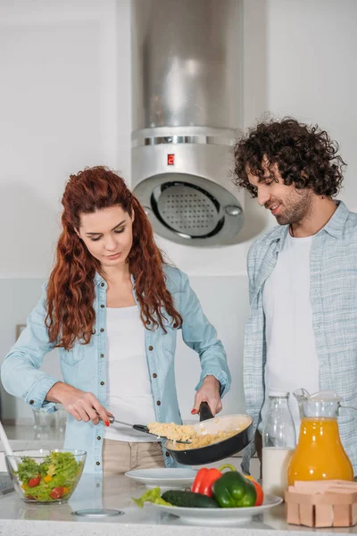 Copine mettre omelette sur la plaque et petit ami à la recherche de nourriture — Photo de stock