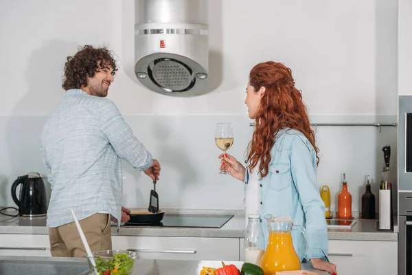 Namorado cozinhar e namorada beber vinho — Fotografia de Stock