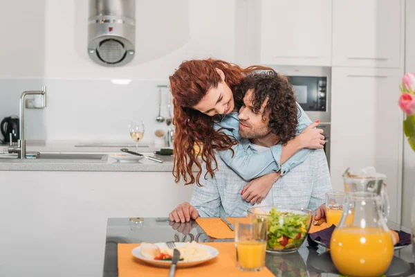 Petite amie heureuse étreignant petit ami de retour à la cuisine — Photo de stock