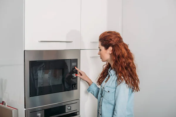 Mulher atraente ligando forno na cozinha — Fotografia de Stock