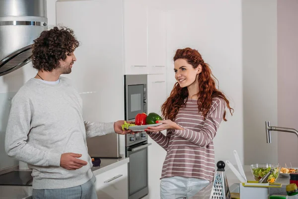 Girlfriend giving boyfriend plate with vegetables — Stock Photo