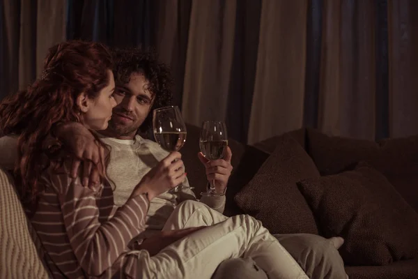 Couple sitting on sofa with glasses of champagne in evening — Stock Photo