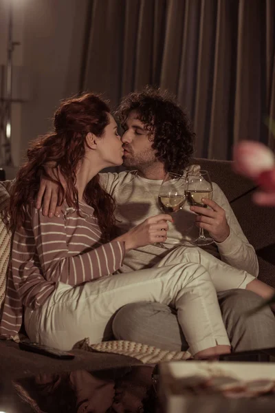 Coppia eterosessuale baciare sul divano in serata — Foto stock