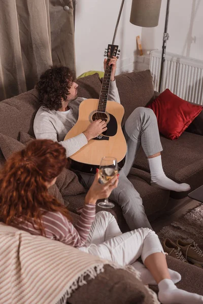 Bonito namorado tocando música com guitarra para namorada em casa — Fotografia de Stock