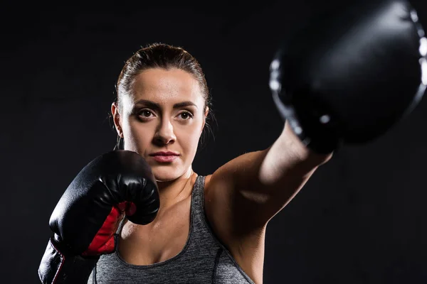 Selective focus of young sportswoman boxing isolated on black — Stock Photo