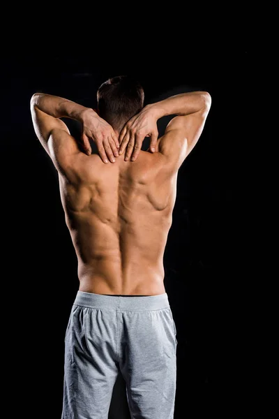 Vista posteriore di sportivo muscoloso senza maglietta in piedi isolato su nero — Foto stock