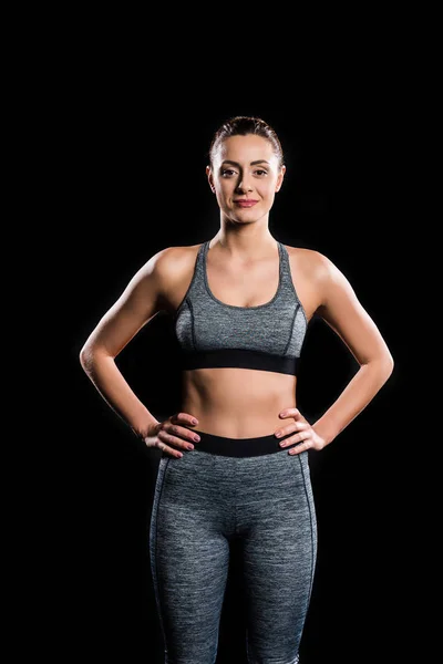Athletische junge Frau in Sportbekleidung blickt vereinzelt in die Kamera auf schwarz — Stockfoto