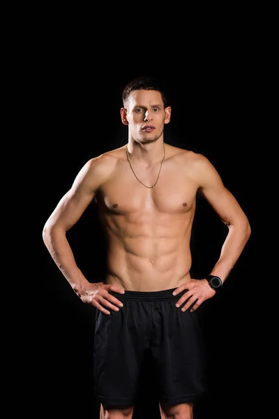 Красивый мускулистый спортсмен без рубашки, смотрящий на камеру, изолированную на черном — стоковое фото