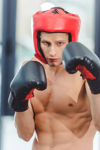 Jeune boxeur musclé torse nu regardant la caméra tout en boxant dans la salle de gym — Photo de stock