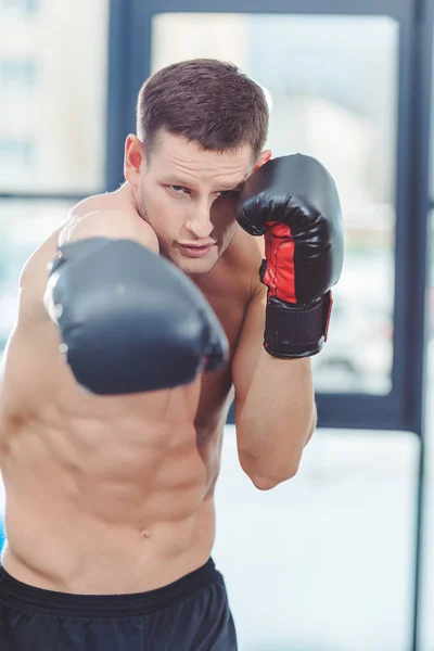 Young caucasian muscular sportsman boxing in gym — Stock Photo