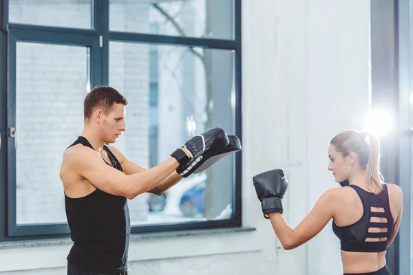 Vista laterale della giovane coppia sportiva pugilato in palestra — Foto stock