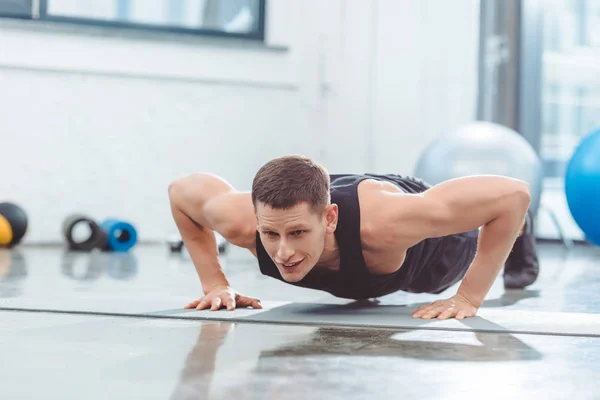 Joven deportista haciendo flexiones en esterilla de yoga - foto de stock