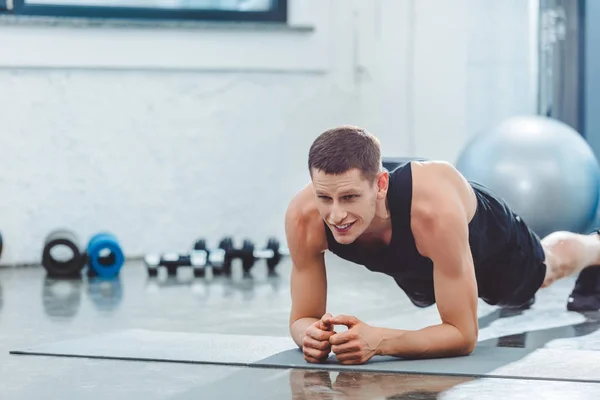Retrato de un joven deportista haciendo ejercicio en la esterilla en el gimnasio - foto de stock