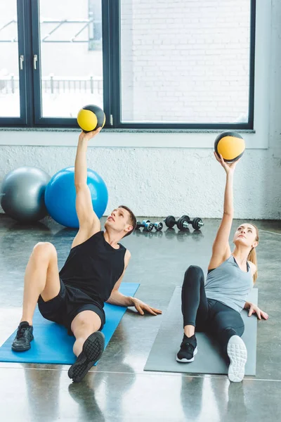Спортивная пара упражняется с мячами вместе в тренажерном зале — стоковое фото