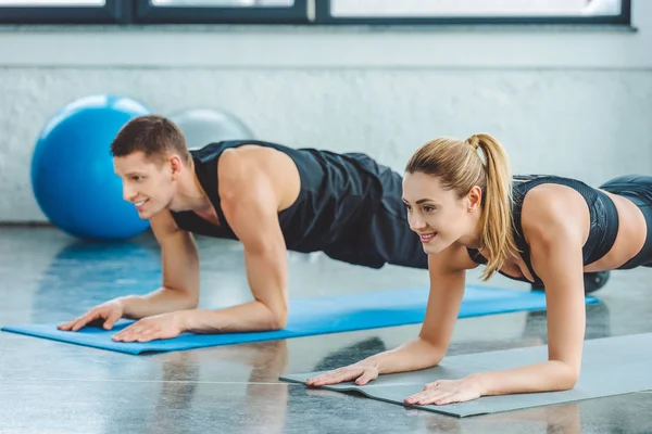 Пара робить відсутні вправи на килимках перед тренуванням у спортзалі — стокове фото