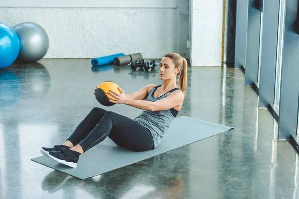 Спортсменка делает упражнения с мячом в тренажерном зале — стоковое фото