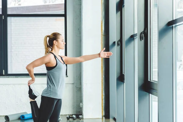 Side view of sportswoman warming up before workout in gym — Stock Photo