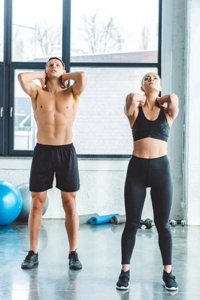 Young couple stretching before workout in gym — Stock Photo