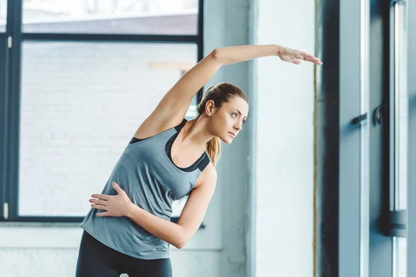 Portrait of young sportswoman warming up before workout in gym — Stock Photo