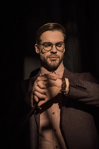 Retrato de homem elegante bonito em óculos verificando relógio de pulso — Fotografia de Stock