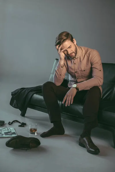 Молодой бизнесмен, страдающий от головной боли, сидя на диване — стоковое фото