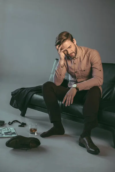 Young businessman suffering from headache while sitting on couch — Stock Photo