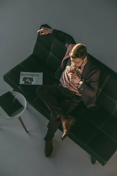 High angle view of young man drinking whisky while sitting on couch — Stock Photo