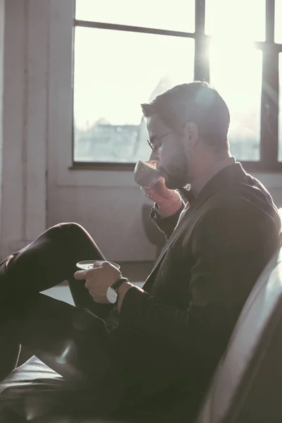 Seitenansicht eines jungen Geschäftsmannes, der drinnen Kaffee trinkt — Stockfoto