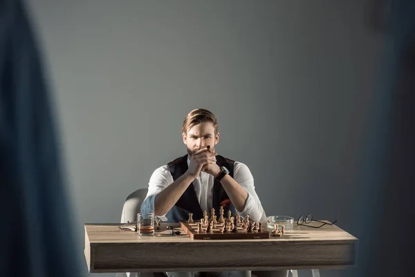 Selektiver Fokus des stilvollen Geschäftsmannes mit Zigarre, der beim Schachspielen in die Kamera schaut — Stockfoto