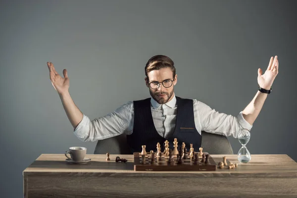 Triumphing young busnessman in eyeglasses looking at camera while playing chess — Stock Photo