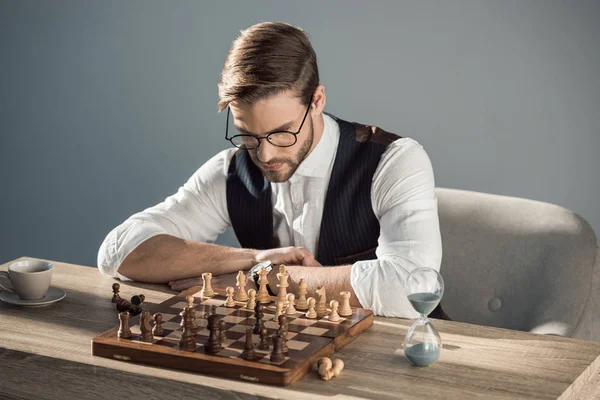 Концентрований молодий бізнесмен в окулярах грає в шахи — стокове фото