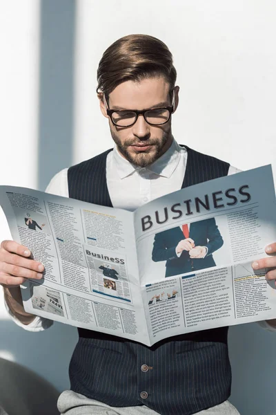 Portrait of stylish young businessman in eyeglasses reading newspaper — Stock Photo