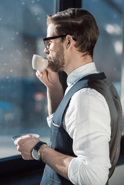 Portrait of fashionable young businessman in eyeglasses drinking coffee — Stock Photo