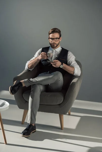 Повнометражний вигляд стильного бізнесмена з чашкою кави, дивлячись на камеру — стокове фото