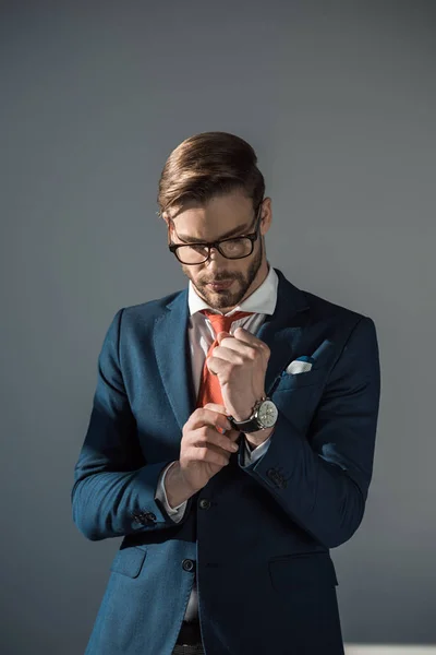 Porträt eines hübschen jungen Geschäftsmannes, der eine Armbanduhr in grau trägt — Stockfoto