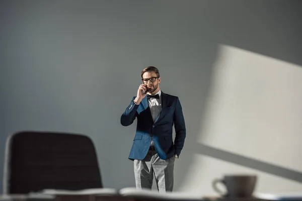 Selective focus of man in eyeglasses and bow tie talking by smartphone — Stock Photo