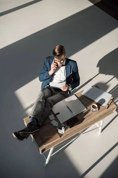 High angle view of fashionable businessman talking on smartphone while sitting at workplace — Stock Photo
